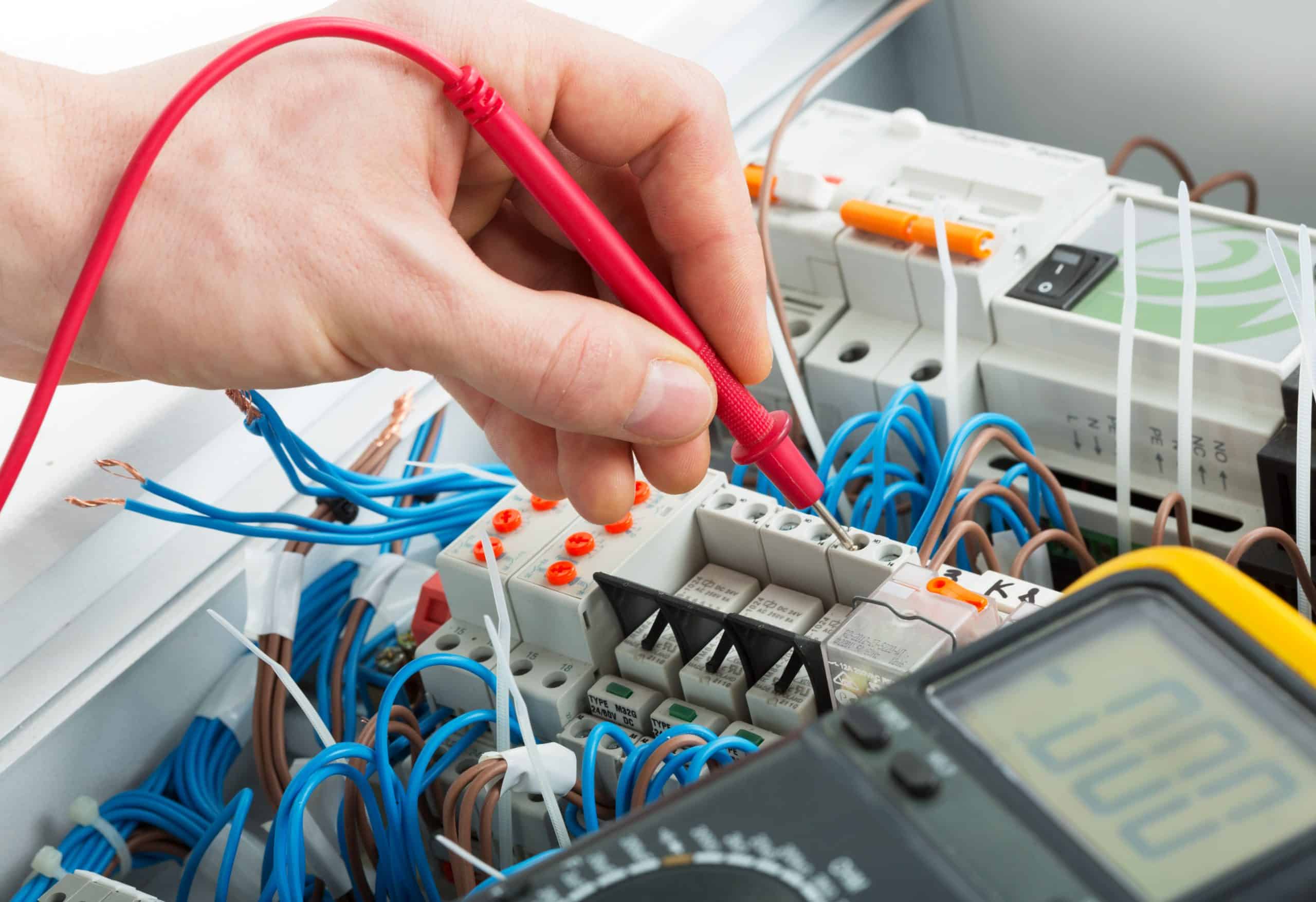 technicien testant un tableau électrique avec un multimètre